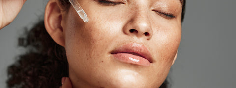 Women applying vitamin c serum on face 
