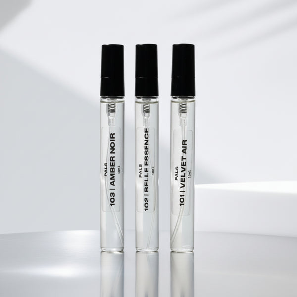 Three perfume bottles with black caps on a reflective surface with a light gray background