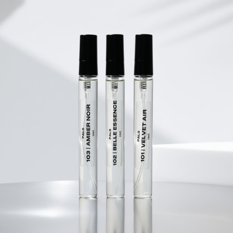 Three perfume bottles with black caps on a reflective surface with a light gray background